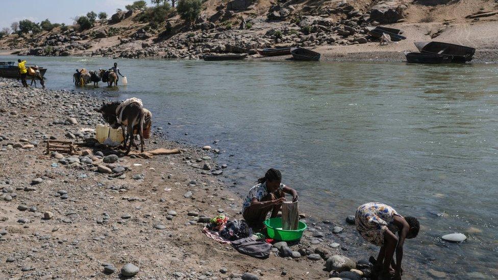 Refugees from the Tigray region of Ethiopia wash their clothes on the Sudanese bank of the Tekeze River with Sudanese locals on December 5, 2020 in Hamdayet, Sudan.