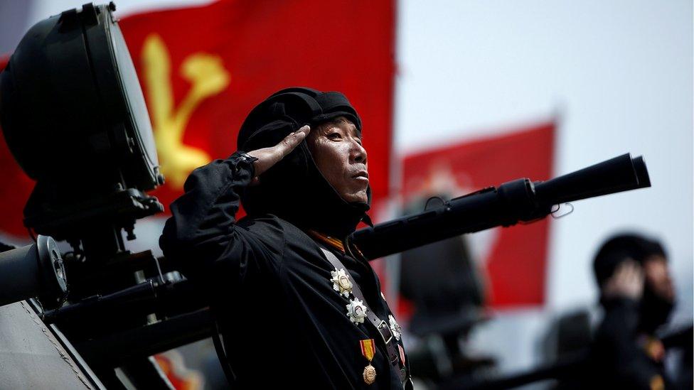 A soldier salutes from atop an armoured vehicle as it drives past the stand with North Korean leader Kim Jong-un during a military parade marking the 105th birth anniversary of country's founding father Kim Il-sung, in Pyongyang, 15 April 2017