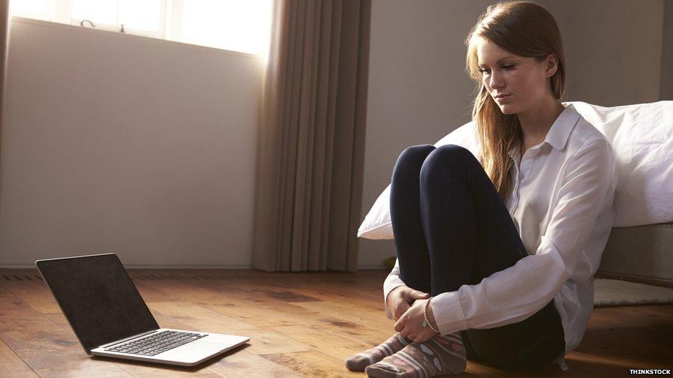 A woman sits by her laptop