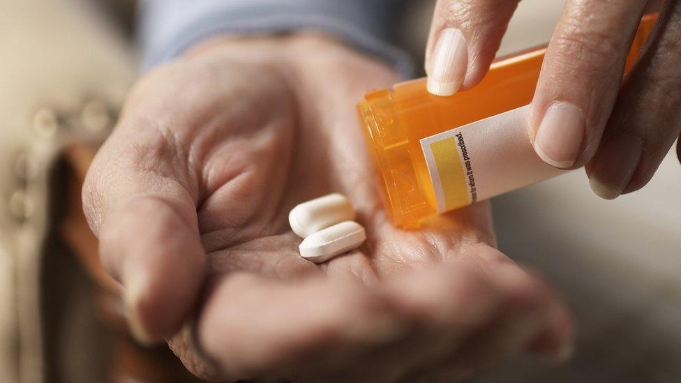 An elderly woman tipping pills into her hand