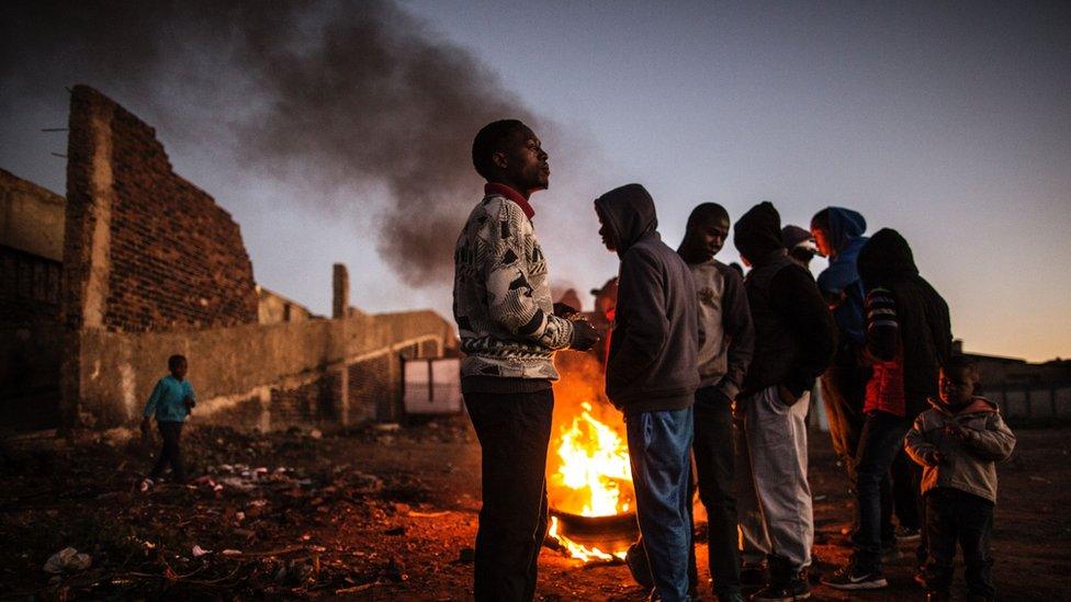 Residents of the Kliptown section of Soweto gather next to burning tyres during a service delivery demonstration on July 27, 2016 ahead of August 3rd municipal elections.