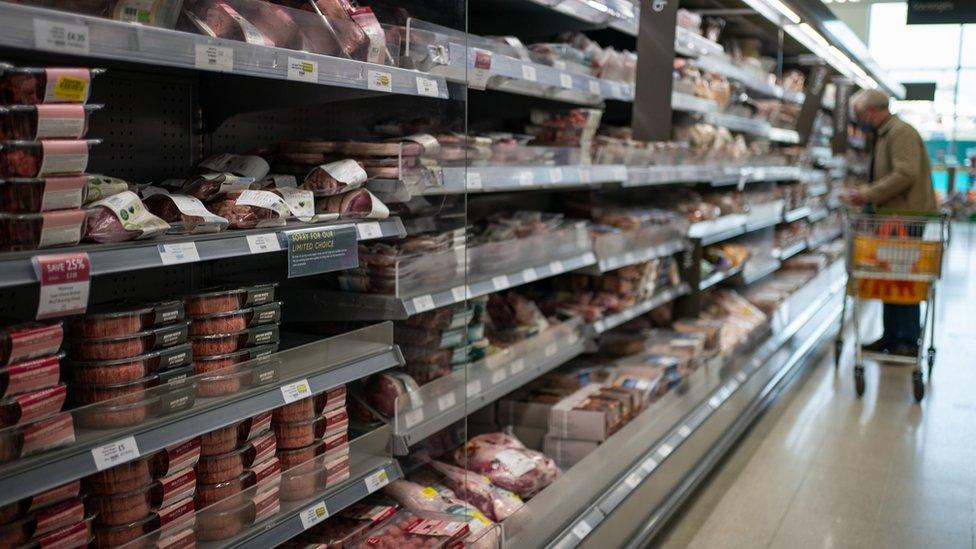 A shopper in the fresh meat aisle in a supermarket