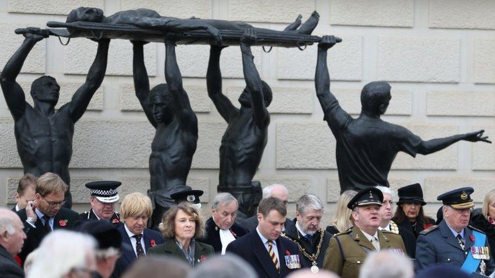 People observe a two minute silence during a service of Remembrance at the National Memorial Arboretum in Staffordshire