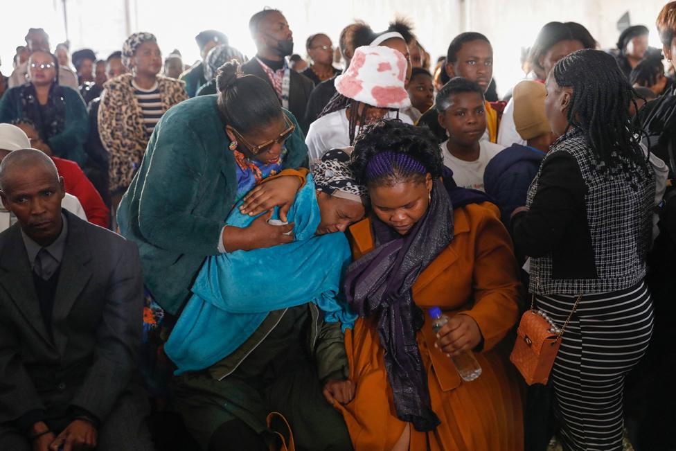 Family members react during a procession of empty coffins at a symbolic mass memorial service in East London on 6 July 2022. In total, 21 young people, mostly teenagers, died in unclear circumstances at a township tavern last month