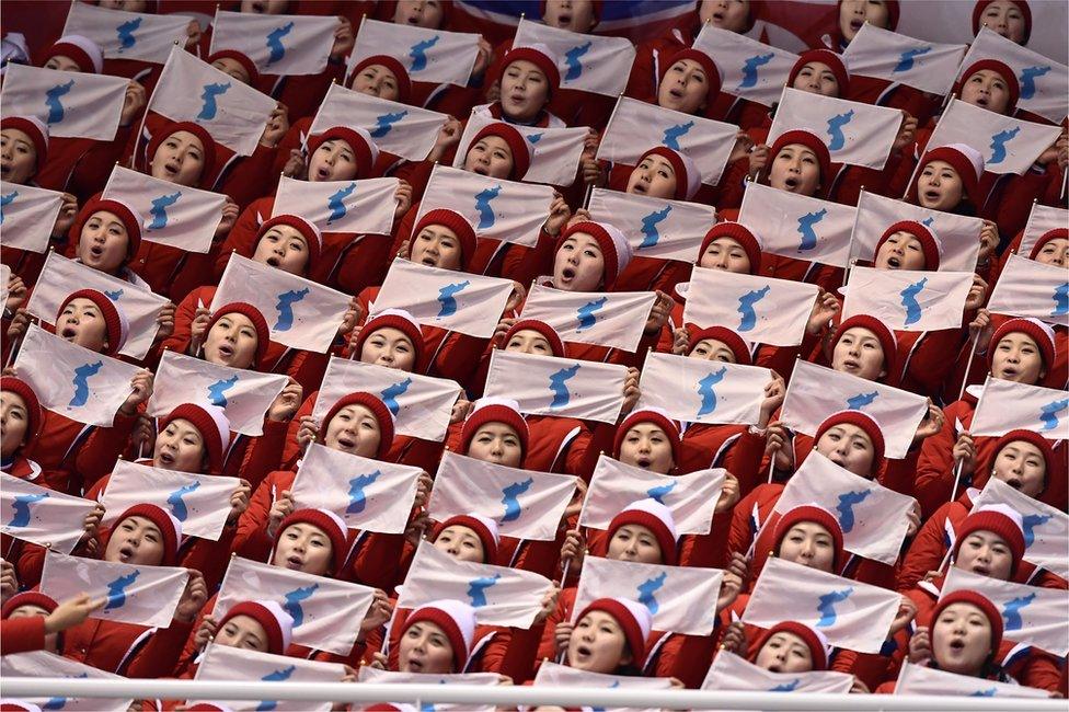 North Korean cheerleaders hold unification flags