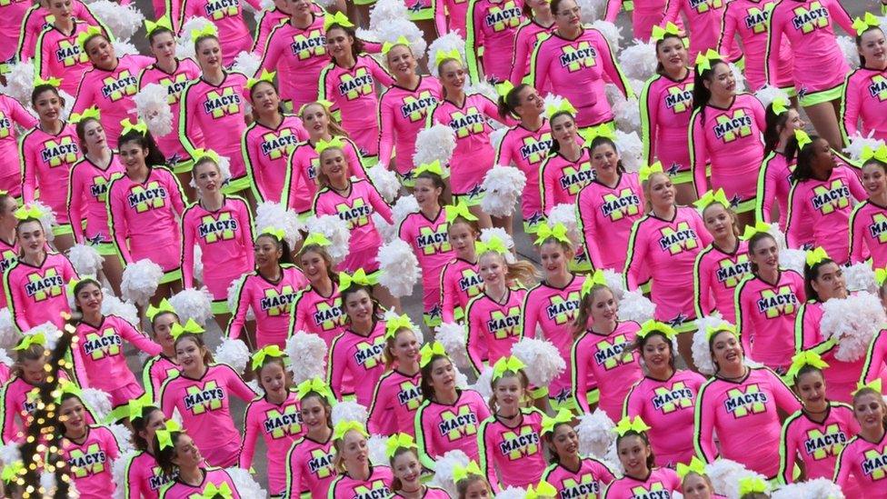 A large group of cheerleaders walk through the street during Macy's Thanksgiving Day Parade