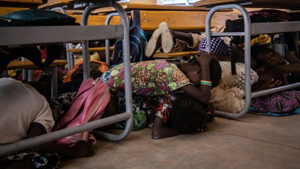 Primary school children lie on the floor of their classroom during an emergency attack simulation in Dori on February 3, 2020