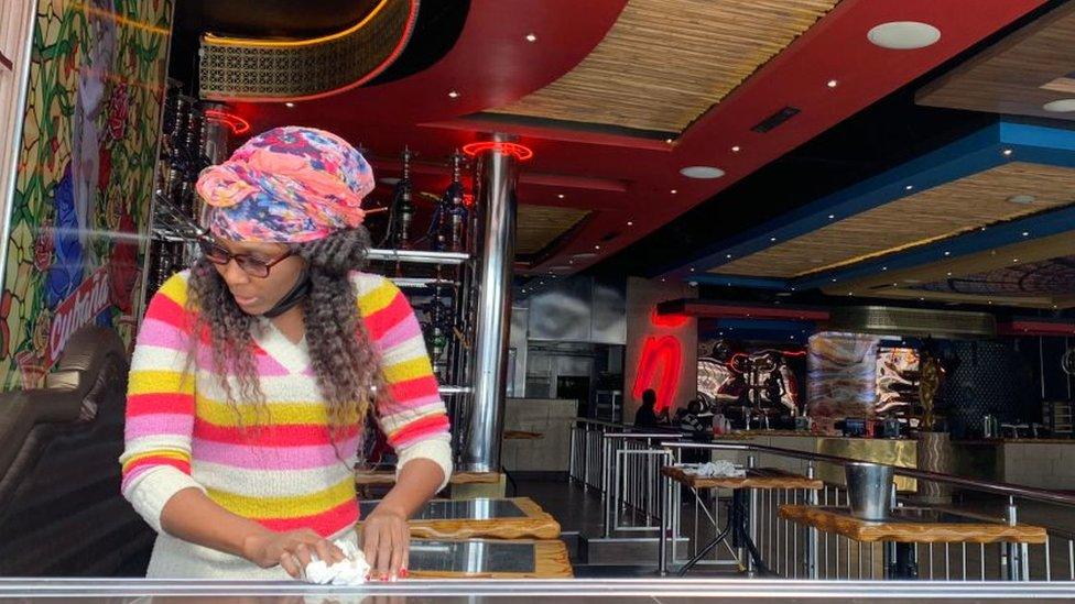 A woman cleaning a table in bar in Johannesburg, South Africa - August 2020