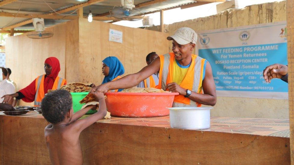 A boy is handed some food at a feeding programme, Bossasso, Somalia