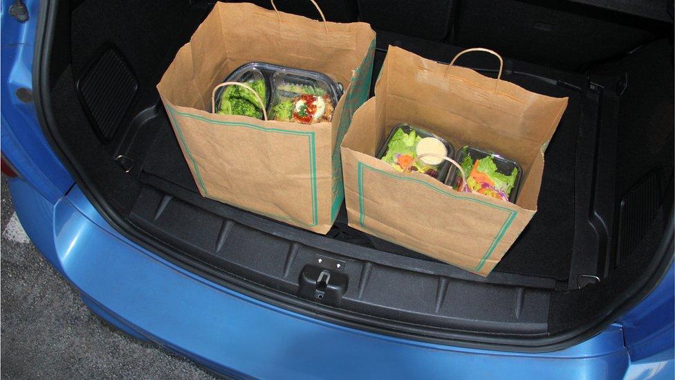 Take-out food in trunk of car using curbside pick-up - stock photo