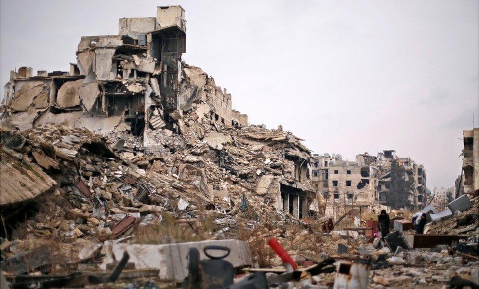 People carry belongings as they walk on the rubble of damaged buildings in the government controlled area of Aleppo, Syria December 17, 2016.