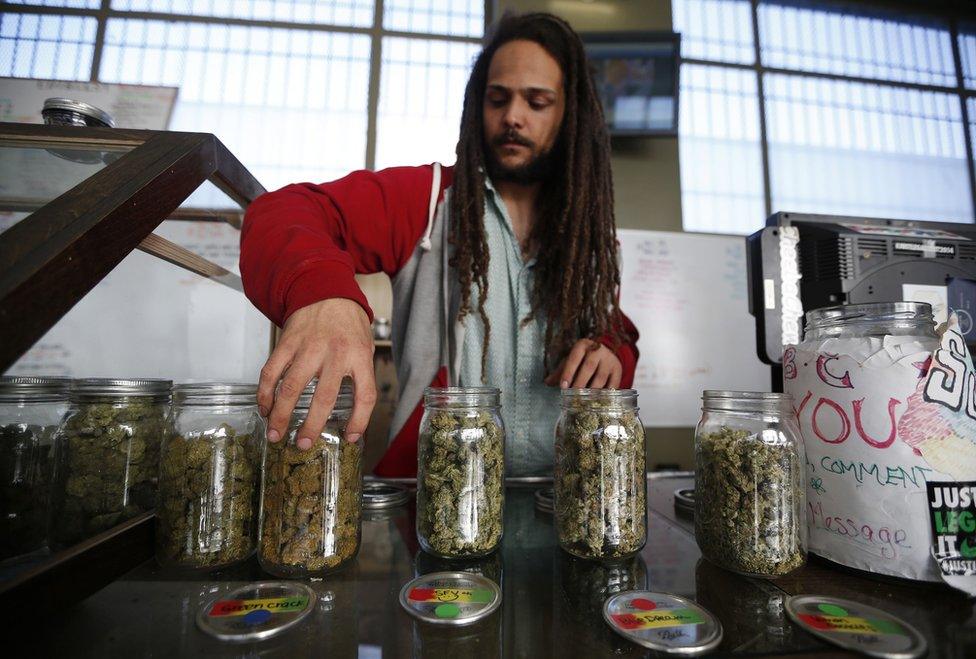 Volunteer Charlie Kirchheimer displays jars of dried cannabis buds at the La Brea Collective medical marijuana dispensary in Los Angeles