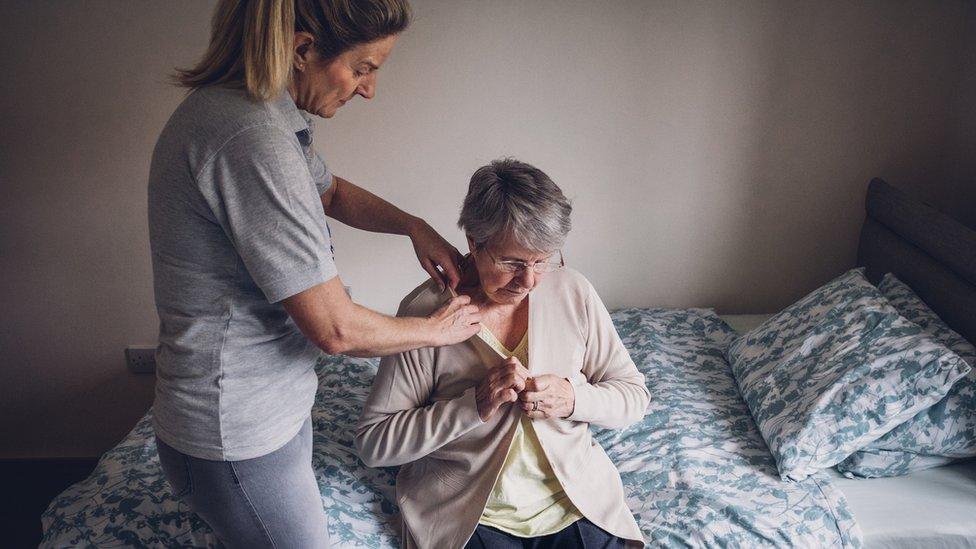 A carer helping a female client in her bedroom