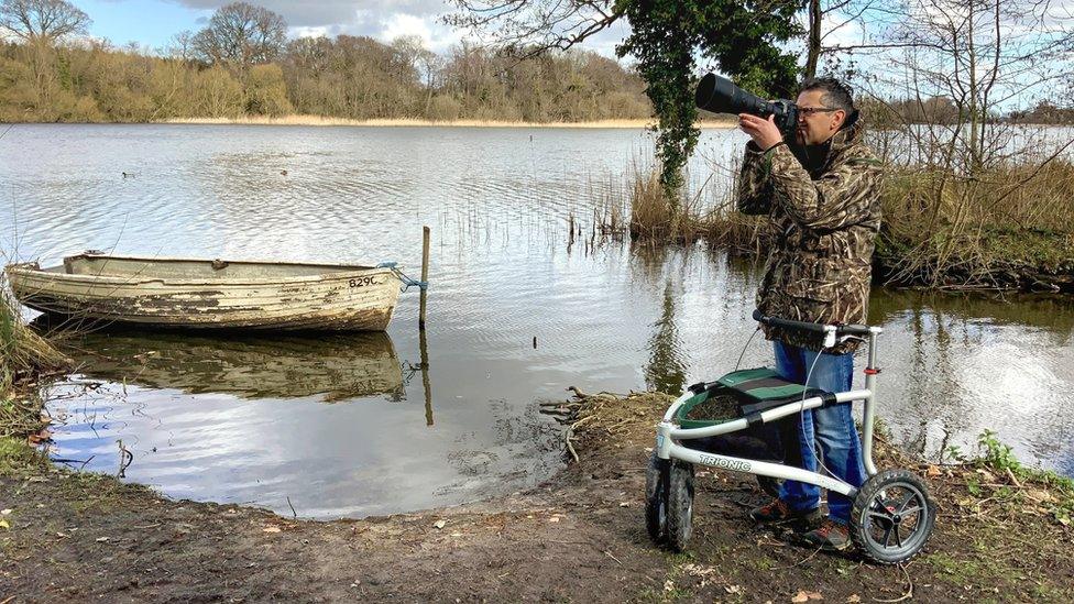 Jon Kelf using his all terrain walker, looking out over a stretch of water with his camera