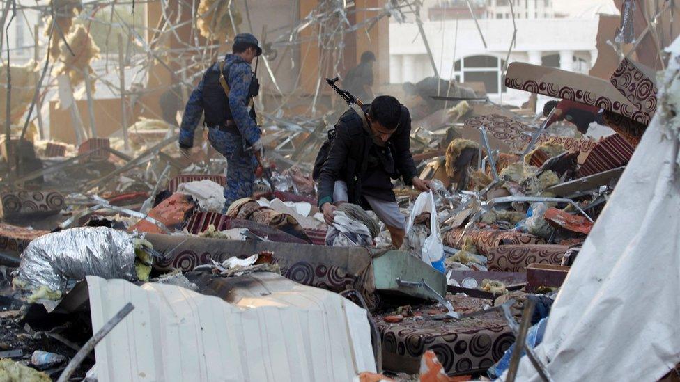 A Yemeni collects items amidst the rubble of a destroyed building following an attack in the capital Sanaa on 8 October