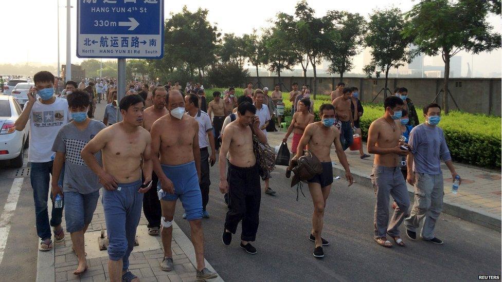 People wearing mask leave their home for temporary shelters near the site of the explosions, at the Binhai new district, Tianjin, August 13, 2015. T