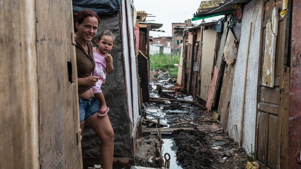 A woman walks inside a favela adjacent to Uniao de Vila Nova