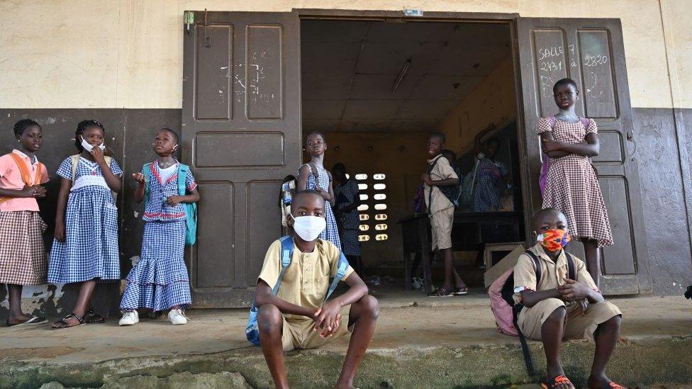 children sit outside school.