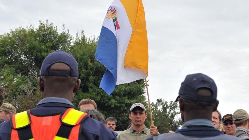 South Africans supporting the white supremacist Afrikaner Resistance Movement (AWB) fly the apartheid-era flag on April 6, 2010 outside a South African court in the north-western town of Ventersdorp, where hundreds demonstrated ahead of the appearance of two men accused of the April 4 killing of far-right leader Eugene Terre'Blanche.