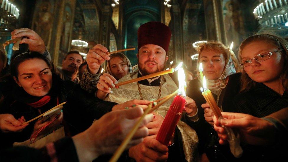 Ukrainians light candles with the Holy Fire during an Orthodox Easter Mass at St Volodymir Cathedral in Kiev