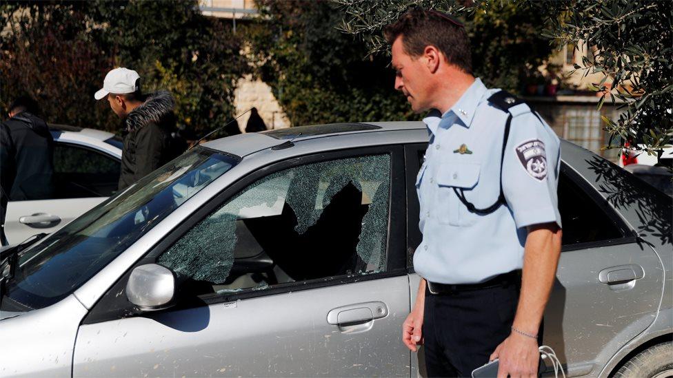 An Israeli policeman looks at a car damaged in a shooting attack in Jerusalem's Old City