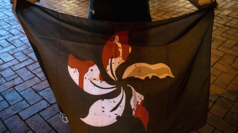 A protester holds a black flag with the Hong Kong emblem in blood at a vigil to commemorate a protester who died 11 months ago during a rally against the controversial extradition law proposal in Hong Kong