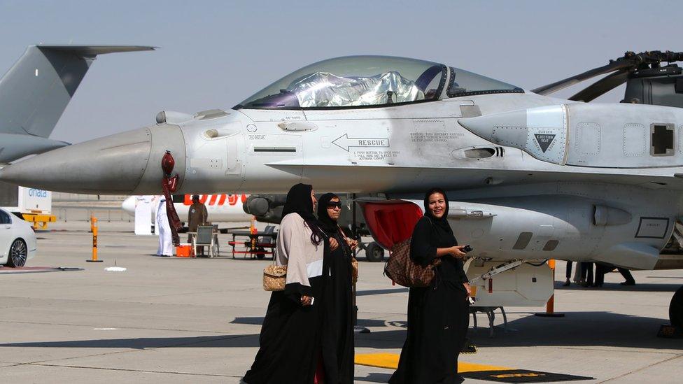 Women walk past a US-made F-16 fighter jet at the Dubai Airshow, 9 Nov 2015