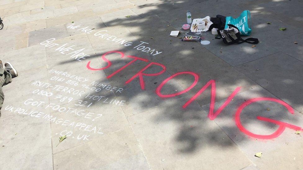 A message saying 'we are grieving today but we are strong' is written on the pavement in Albert Square