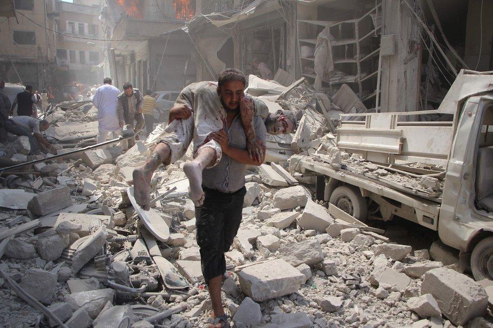 A man carries an injured man in Idlib, Syria, 10 September