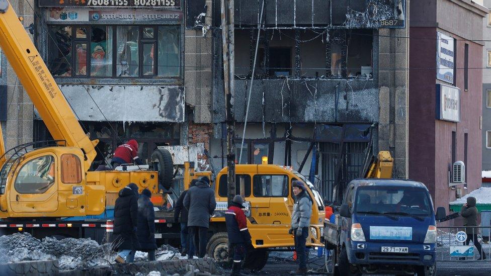 People stand outside a building damaged by an explosion after a truck carrying liquefied natural gas crashed, in Ulaanbaatar, Mongolia January 24, 2024.