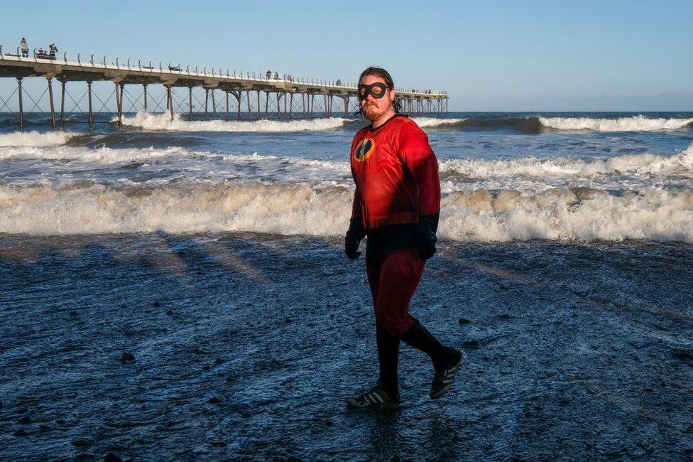 A swimmer in fancy dress leaves the chilly water of the North Sea after taking part in the New Year Day Dip in Saltburn