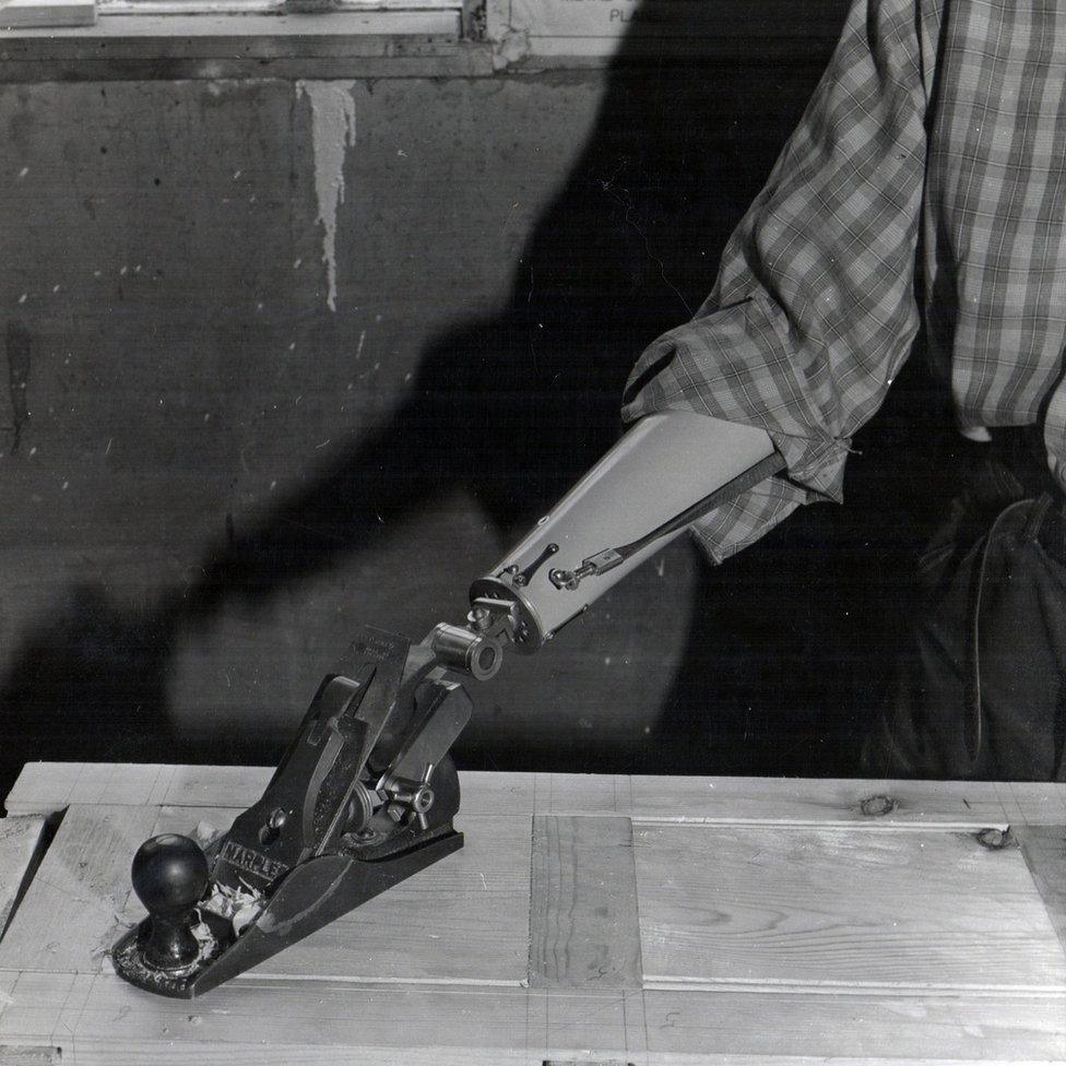 A man with a wood plane attached to his arm