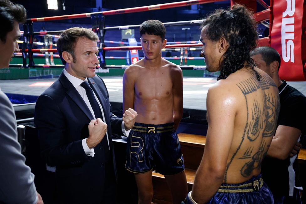 France's President Emmanuel Macron (L) speaks with Muay Thai fighters during a visit to Rajadamnern Muay Thai Stadium in Bangkok on 17 November 2022