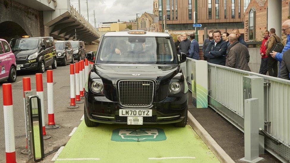 A specially-adapted black cab charging up wirelessly