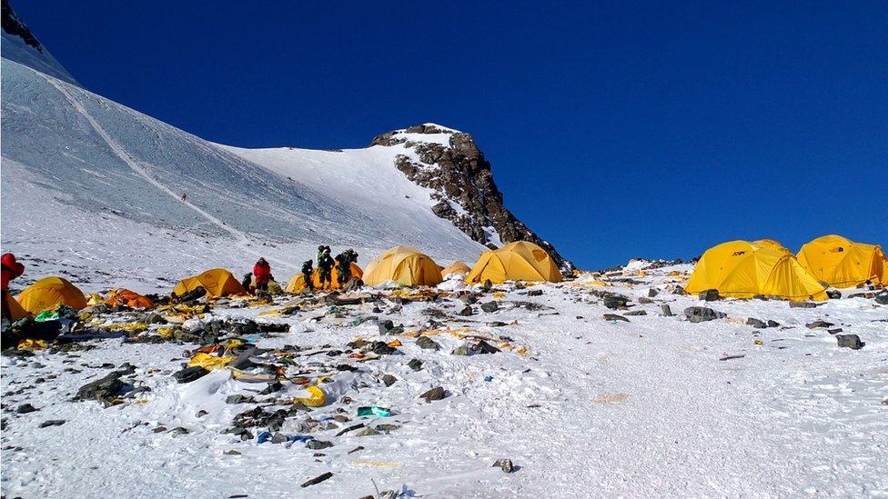 Next to yellow tents, discarded climbing equipment and rubbish left scattered at Camp 4