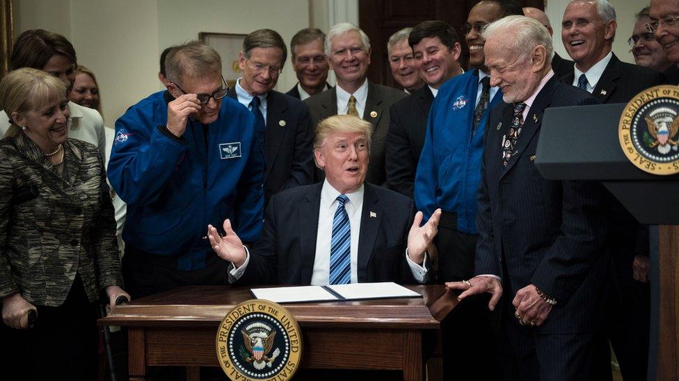 David Wolf (CenterL), former NASA astronaut, and Buzz Aldrin (Center R), former NASA astronaut and second man on the moon, watch with others before US President Donald Trump signs an executive order about space exploration in the Roosevelt Room at the White House June 30, 2017 in Washington, DC