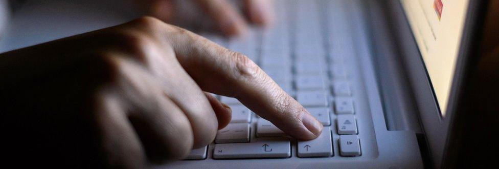 A hand pressing a key on a laptop keyboard