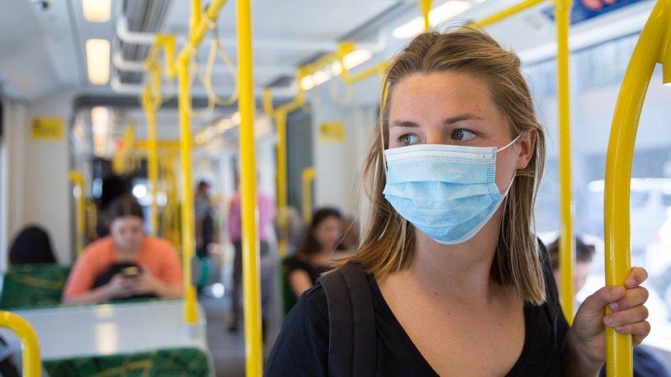 A woman on a train wearing a mask