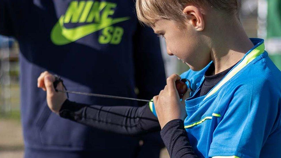 A boy holding a conker and a string