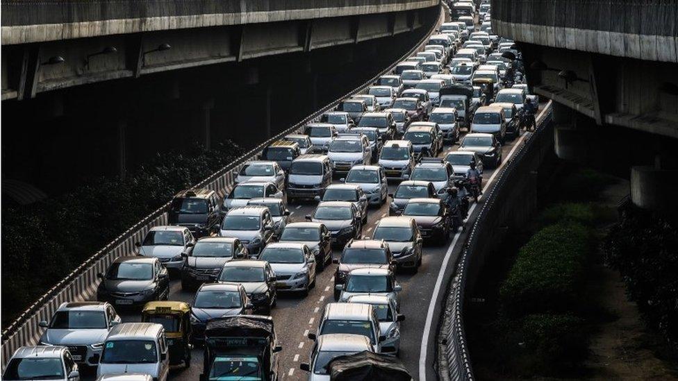 A stream of cars backs up on an exit to a highway in New Delhi. India's capital, with 18 million residents,