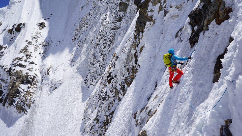 A climber going up a sheer cliff face