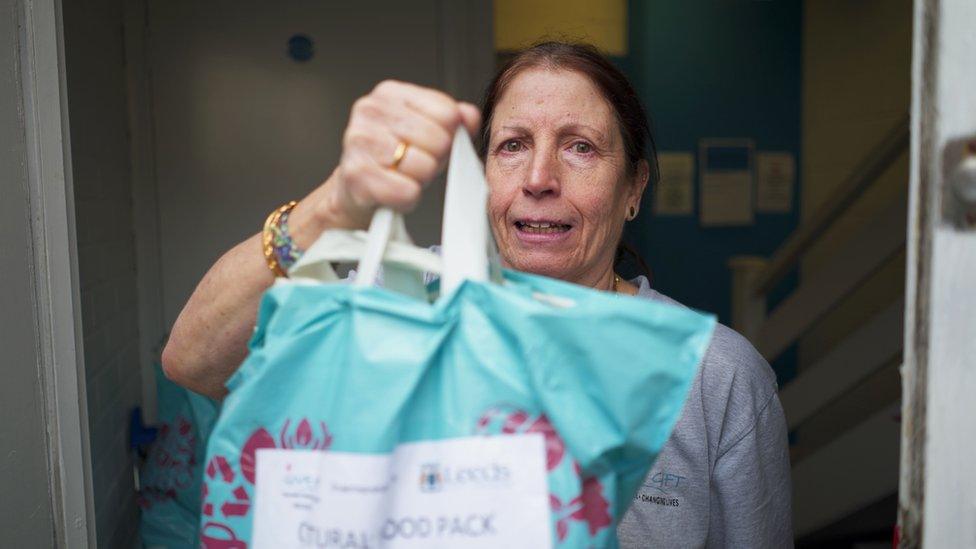 Janice, stood in the food hub doorway holding a blue bag full of food