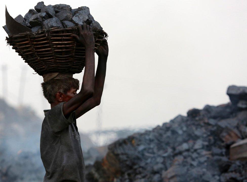 An Indian worker carries a basket of coal collected at a mine in the state of Jharkhand.