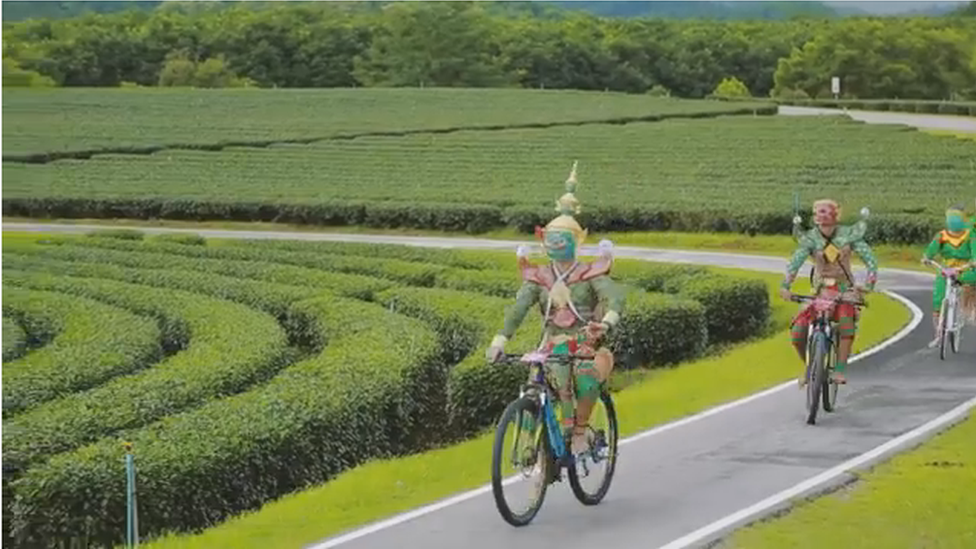 A still from the video showing the characters riding on bikes