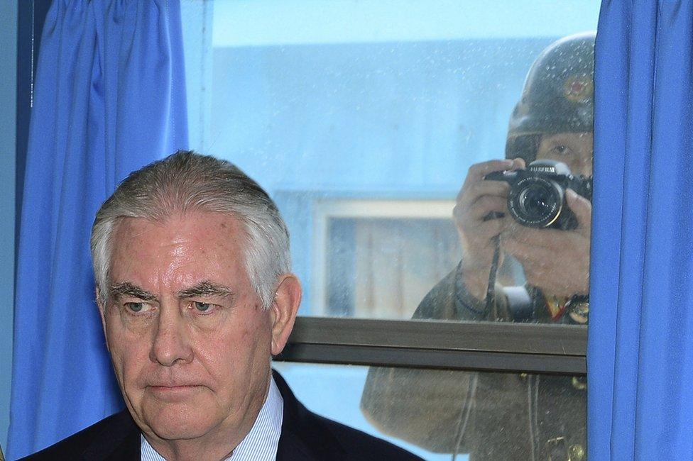 A North Korean soldier, right, tries to take a photograph through a window while Rex Tillerson visits the border village of Panmunjom, which has separated the two Koreas since the Korean War, 17 March