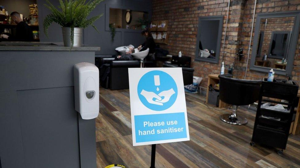 A sign asking for people to use hand sanitizer as they enter a business