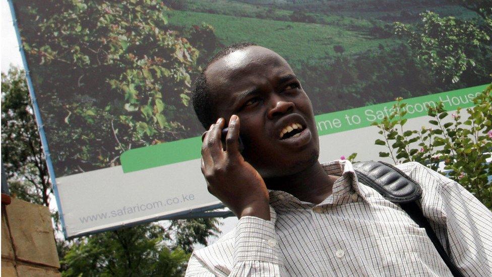 A man talks on a mobile phone while standing next to a huge Safaricom bill board after the launch of the Initial Public Offer (IPO) shares in Nairobi 28 March 2008.