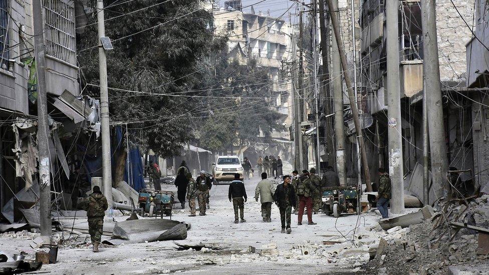 Syrian pro-government troops walk through the streets with civilians in eastern Aleppo, Syria, 12 December 2016