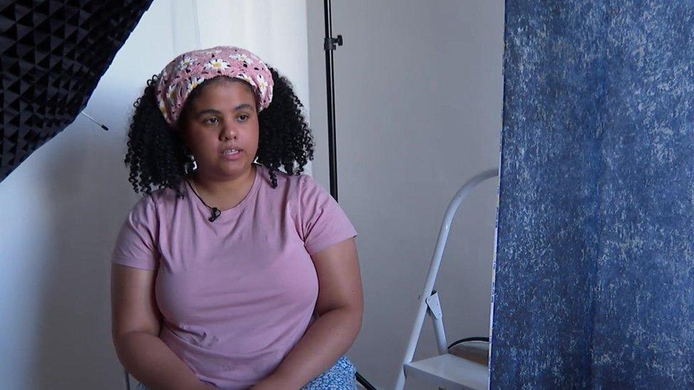 Sophie Godfrey, a woman with curly dark hair in a pink headscarf, speaking in her studio.