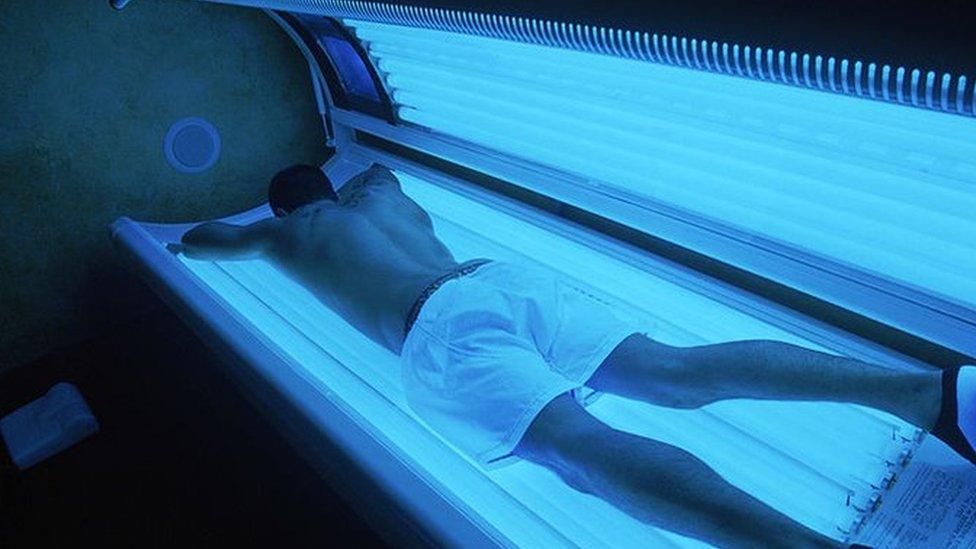 Man using a tanning salon bed